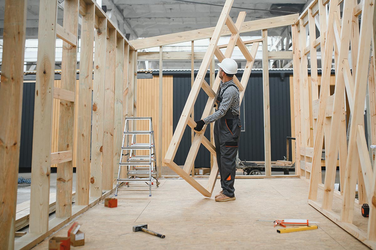 Carpenter positioning a timber frame inside a building